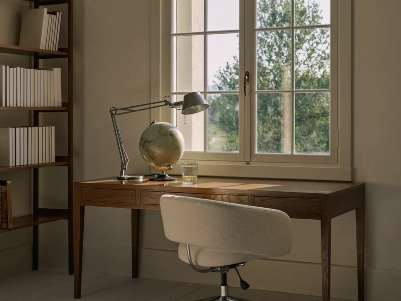 Stille studiehjørne ved vindue med lampe, bogreol og tom stol